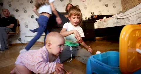 Toddler crawling reaching toy while family plays Stock Footage 295276358