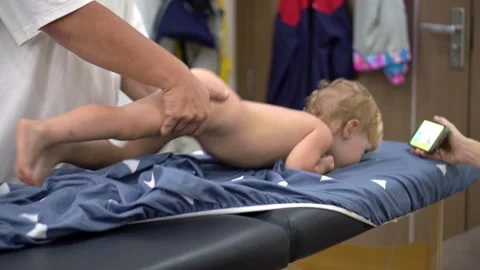 Toddler crawling toward a smartphone during a wellness massage session Stock Footage 341241660