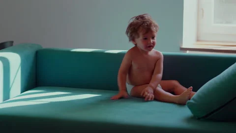 Toddler diving onto sofa cushion at home, capturing fearless play, joyful m.. Stock Footage 340449529