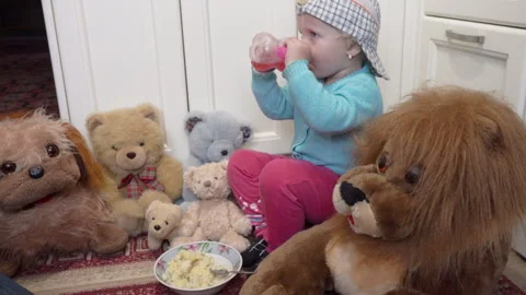 Toddler drinking water next to teddy bears and a lion Stock Footage 340512336