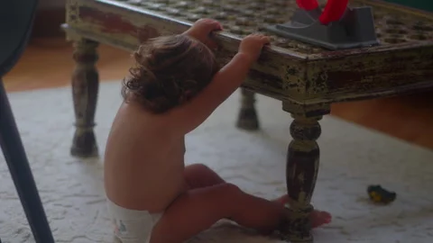 Toddler dropping toy car through holes in rustic coffee table during mornin.. Stock Footage 335699635