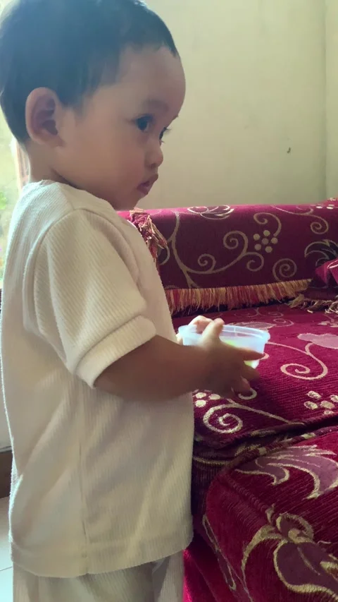 Toddler eating a green grape from a small bowl at home Stock Footage 344104542