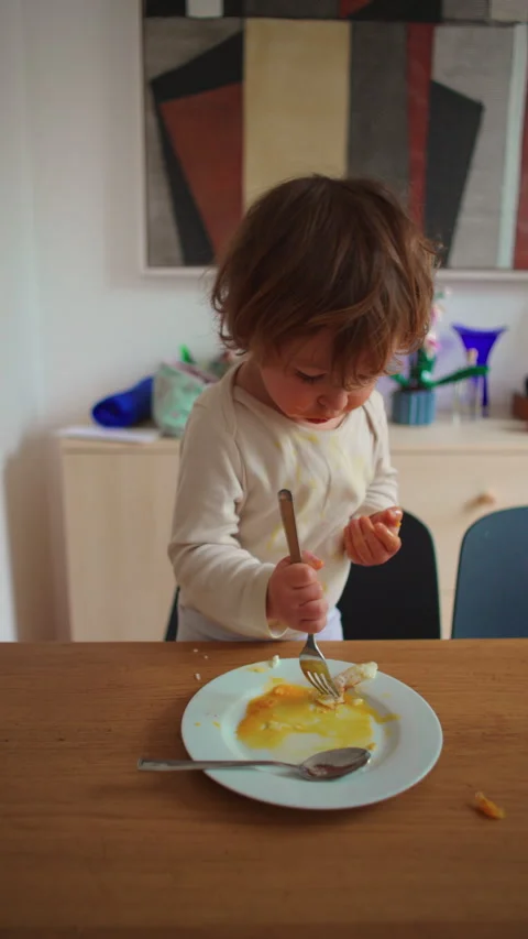 Toddler eating scrambled eggs with a fork by himself 動画素材 348943500