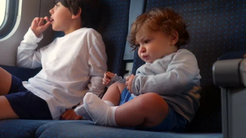 Toddler eating snack while riding passenger train beside older sibling, aut.. Stock Footage 338121455