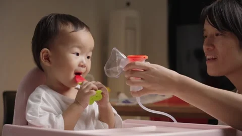 Toddler Eating Watermelon While Receiving Nebulizer Treatment at Home 動画素材 339078120