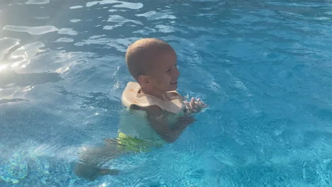 Toddler Embraces Summer Fun, Learning to Swim Safely in a Shimmering Blue Pool Stock Footage 318205437
