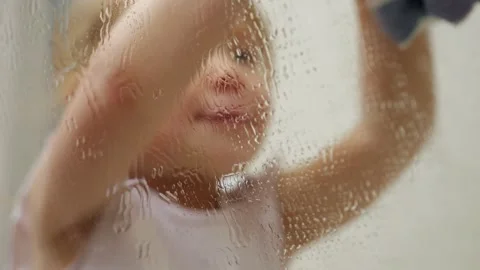 Toddler engaging in the joyful task of cleaning a wet window Video stock 303878663