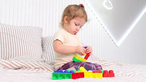 Toddler explores creativity while building with colorful blocks in cozy room Stock-Footage 295352392