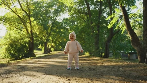 Toddler explores nature path in sunny park surrounded by trees Stock Footage 307120013
