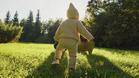 Toddler exploring a sunlit garden while parent watches closely Stock Footage 307118249