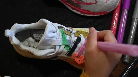 Toddler girl decorates her trainers with coloured marker pens. Stock Footage