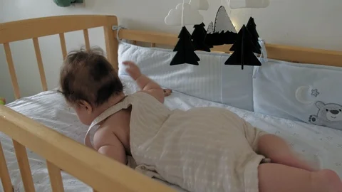 Toddler girl learning to keep her head lying in a crib. Stock Footage 116472083