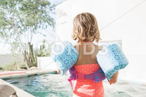 Toddler girl in water wings at edge of swimming pool Stock-Fotos