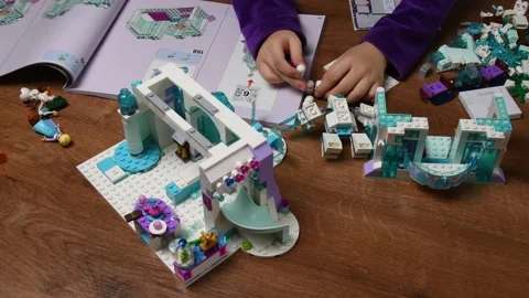 Toddler hands takes tiny Lego snowman and put in a row while playing Lego blocks Video stock 146072219