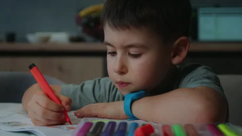 Toddler happily drawing at table with red marker, hand on cheek Stock Footage 275251280