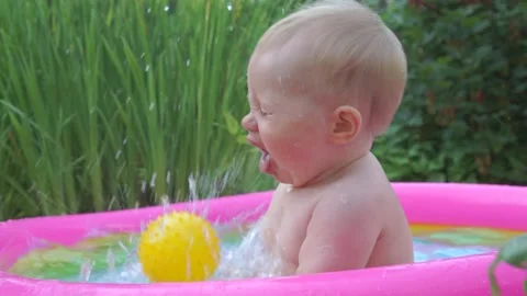 Toddler having fun in the pool playing with a ball Vídeos de archivo 157399771