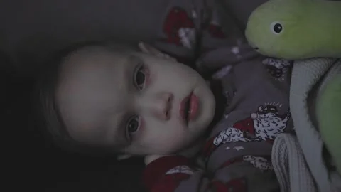 Toddler with high temperature sitting sofa in living room gray pajamas sick baby Video stock 242420651
