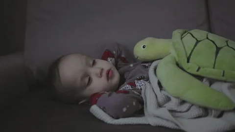 Toddler with high temperature sitting sofa in living room gray pajamas sick baby Stock-Footage 242420666