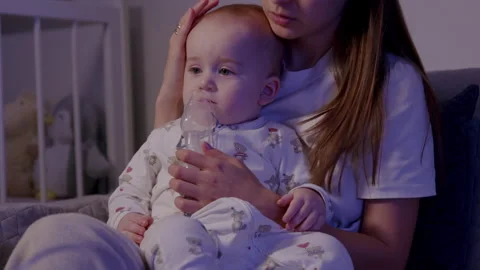 Toddler inhalation procedure during cold season, captured in a cozy indoor Stock Footage 323234829