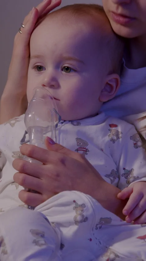 Toddler inhalation procedure during cold season, captured in a cozy indoor Stock Footage 323498667