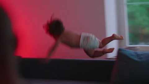 Toddler launching onto couch during playful jump, highlighting fearless exp.. Stock Footage 340426925