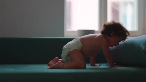 Toddler leaping through the air onto sofa at home, capturing fearless play,.. Stock Footage 340430275