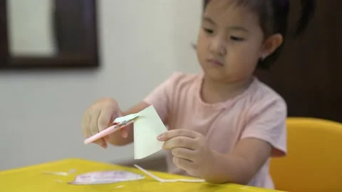 Toddler learning to use scissor to cut a paper Stock Footage 159056517