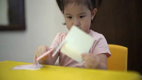 Toddler learning to use scissor to cut a paper Stock Footage 159056524