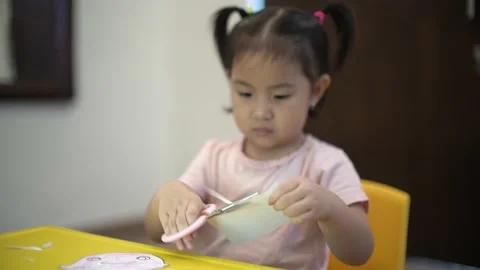 Toddler learning to use scissor to cut a paper Stock Footage 159056571