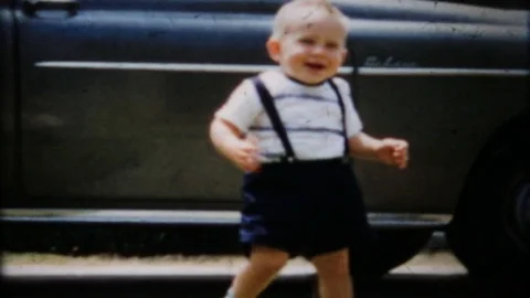 Toddler learns to walk on grass in frontyard 1950s vintage film home movie 4417 Stock Footage 83566770