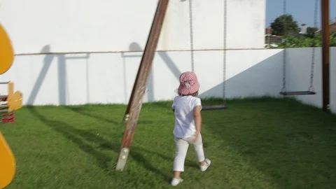 Toddler makes a funny attempt to sit herself in the swing, How not to do Stock Footage 97763706