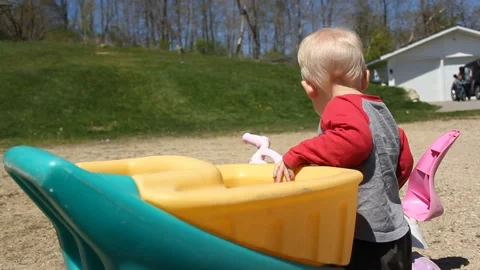 Toddler Mounts Trike While Watching Brother Video stock 130758281