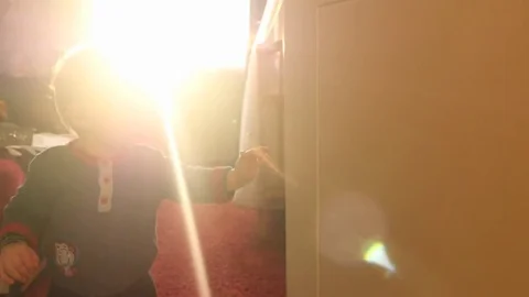 Toddler opens and closing door against flashing sun in window Stock Footage 84161059