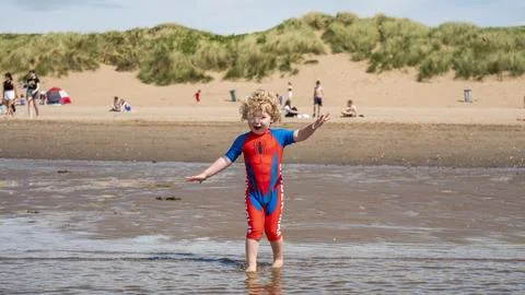 Toddler paddling on a sandy beach in the summer time Stock Photos