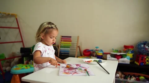 Toddler painting at a table with brush while sharing art at house event Stock Footage 287885121
