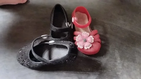 The toddler picks up and puts back the black and red shoes Stock Footage 224796101