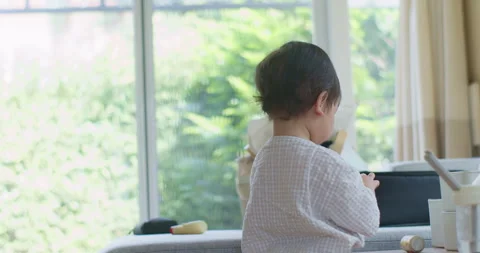 Toddler playing alone on a sofa in a brightly lit living room Stock Footage 348161036
