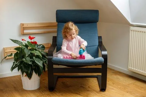 Toddler playing with a construction kit while seated in a cozy chair at home Stock-Fotos