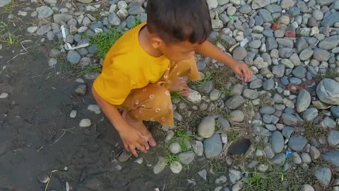 A toddler is playing on the rocks Stock Footage 197375443