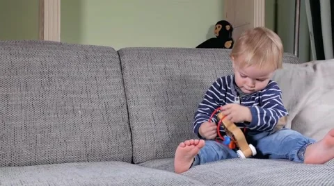Toddler playing with a toy on the couch Stock Footage 61780888