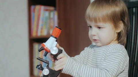 Toddler playing with a toy microscope. The child learns the world. Educational Stock Footage 151703441