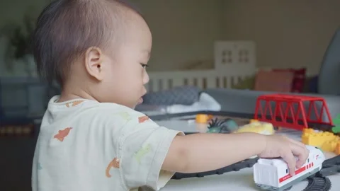 Toddler Playing with Toy Train in Bright Room Stock Footage 341143262