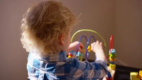 Toddler plays with roller coaster bead toy in over the shoulder perspective Stock Footage 94635720