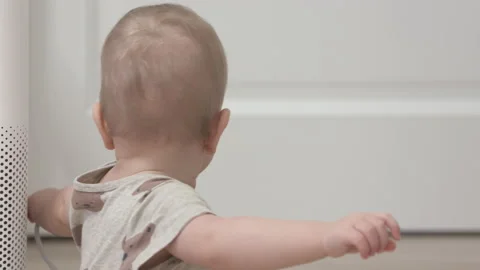 Toddler pulls the electric plug out of socket, 1 year old infant playing with Stock Footage 172077961