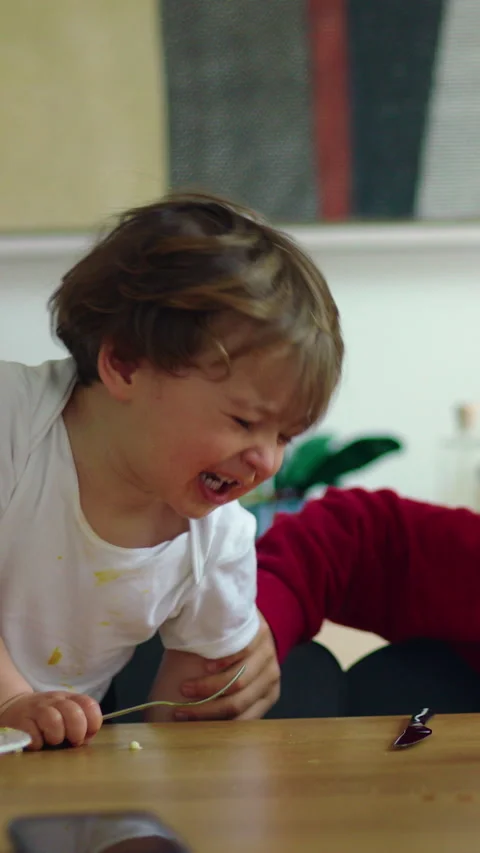 Toddler reaches for sibling breakfast mug causing playful family conflict, .. Stock Footage 336545344