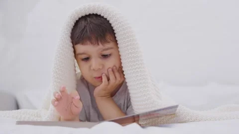 Toddler reading a book on a bed at home Stock-Footage 244733352