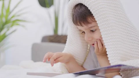 Toddler reading a book on a bed at home Stock Footage 246133236