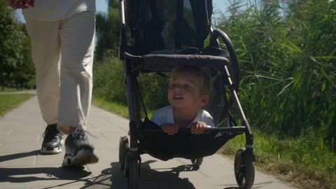 Toddler rides in the stroller, lying in the storage compartment under the seat. Stock Footage 307861388