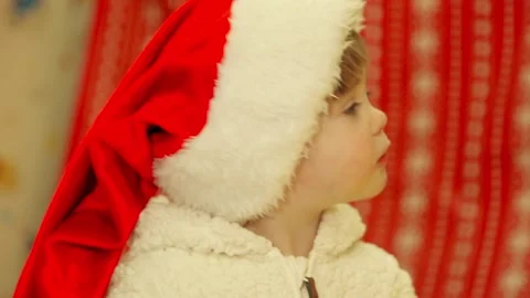 Toddler in a Santa Claus hat eats an apple Stock Footage 144475434