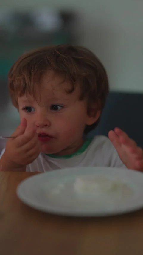 Toddler scooping ice cream with spoon at dining table, developing fine moto.. Stock Footage 340415858